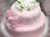 Этот свадебный торт сделан в два яруса, которые покрыты розовой глазурью, ...