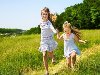 Группа детей, бегущих по зеленой траве на открытом воздухе.