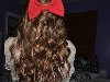 Красный бантик на волнистых волосах шатенки